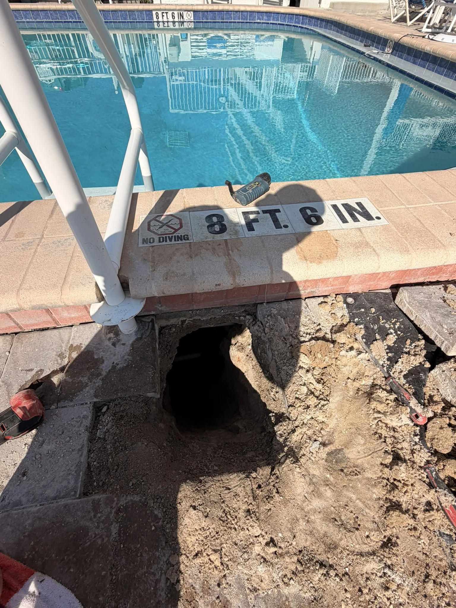 Pavers removed and the ground tunneled under the pool deck to reach the broken pipe — Daytona Beach Shores, FL