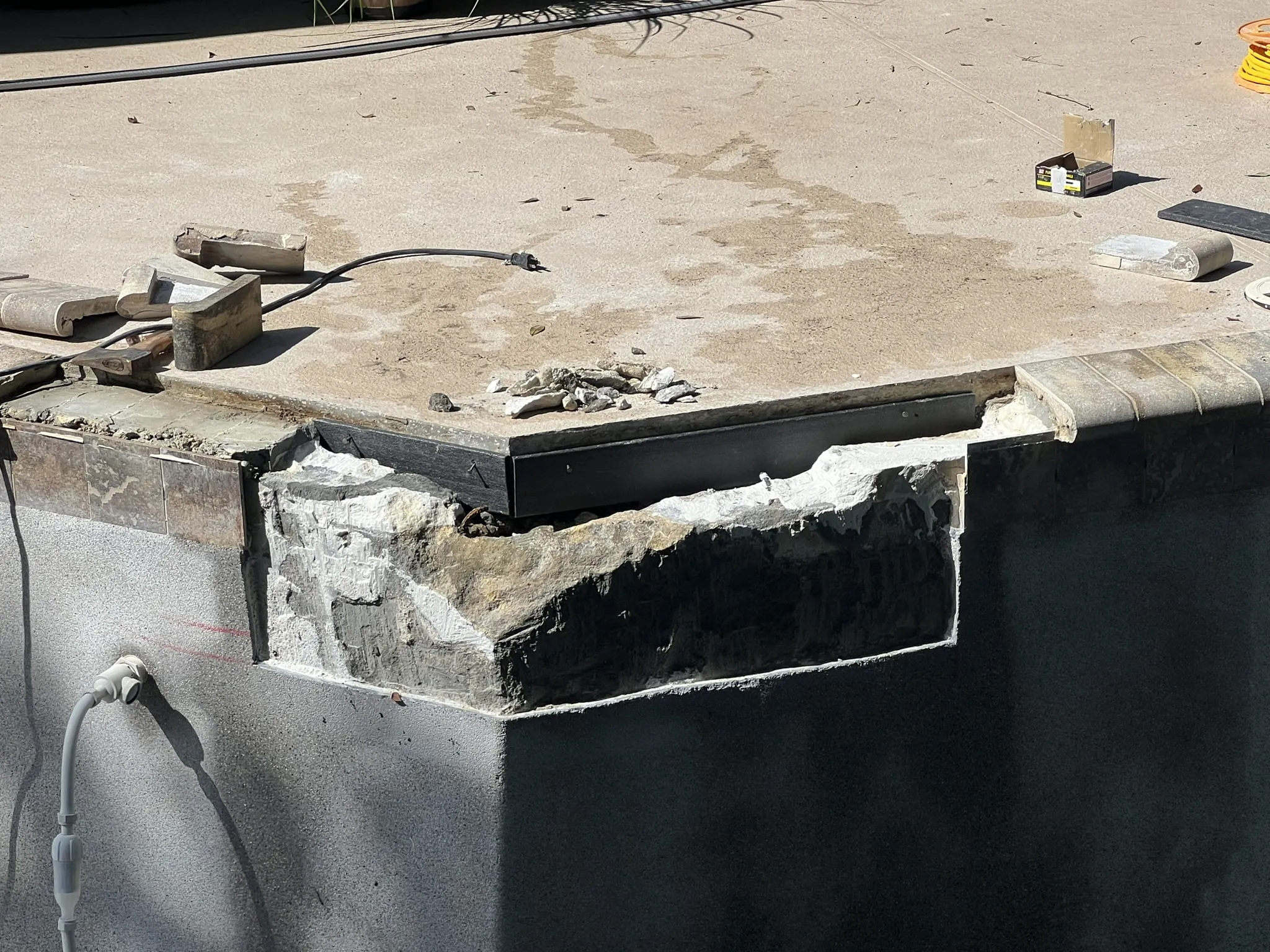 Damaged bond beam section demoed out with original coping and tile saved — Longwood, FL