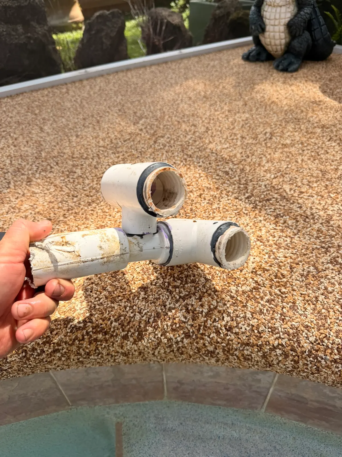 The removed venturi therapy jet fitting held above the pool deck — New Smyrna Beach, FL
